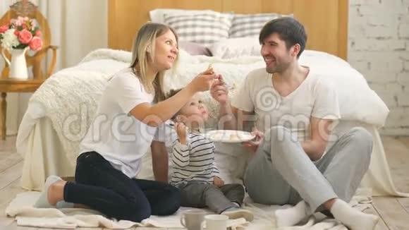小可爱的男孩和爸爸妈妈在卧室里吃蛋糕视频的预览图