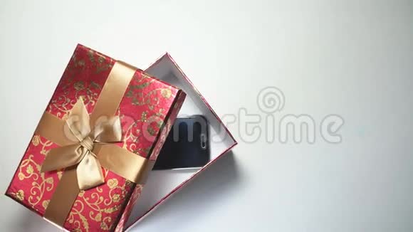 白色背景下红色礼品盒中的智能手机4K视频的预览图