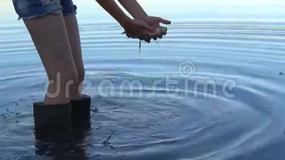 女孩的手握着鱼夏天让它进入池塘视频的预览图