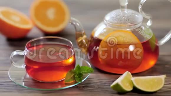 玻璃茶壶和一杯黑茶上面放着橘子柠檬石灰和薄荷视频的预览图