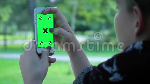 年轻女孩晚上拿着绿色屏幕的智能手机随意的生活方式视频的预览图