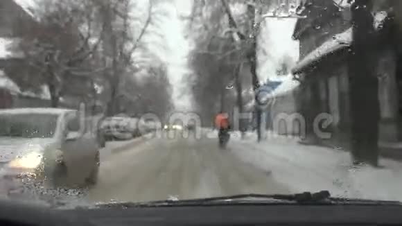 城市街道的恶劣驾驶条件骑自行车的人在雪地冰冻的道路上开车视频的预览图