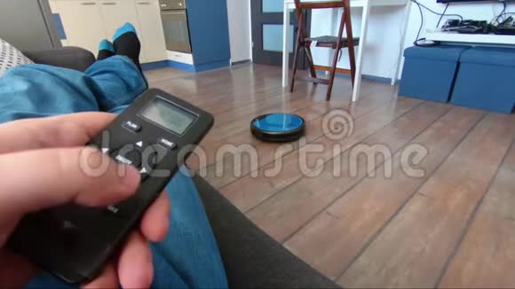 在沙发上放松的人手里拿着机器人吸尘器遥控器视频的预览图