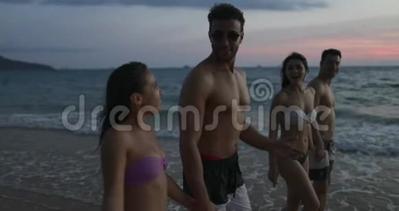 在夕阳下的沙滩上散步的朋友小组说年轻人在海上度假快乐视频的预览图