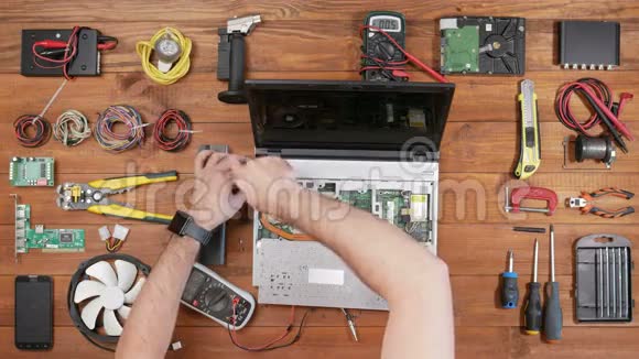 男工程师用螺丝刀拆卸笔记本电脑木桌顶景视频的预览图