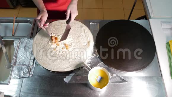 女厨师在炒菜时在厨房里用专业的烤炉做煎饼锅上煎煎饼的过程视频的预览图
