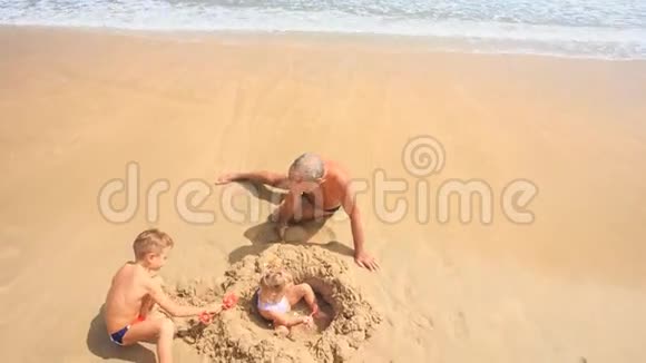 镜头移离爷爷孩子们在沙滩堆中玩耍视频的预览图