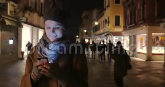 女人在晚上散步在手机上聊天视频的预览图