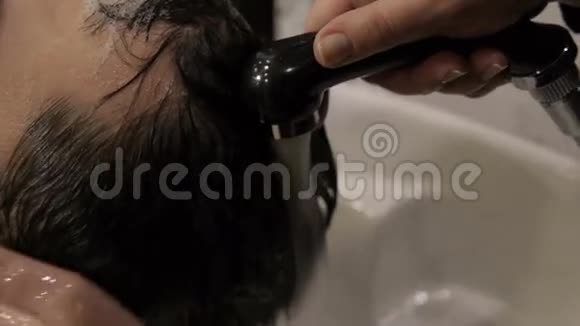 黑发男子理发师在水槽里洗头视频的预览图