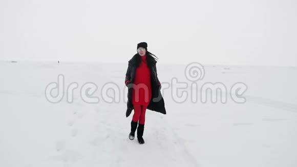 穿着红色紧身衣和靴子的女孩在冰冻的海湾上视频的预览图