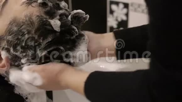 黑发男子理发师在水槽里洗头视频的预览图