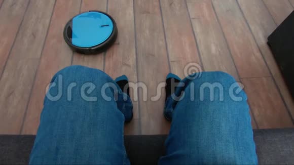 在沙发上放松的人手里拿着机器人吸尘器遥控器视频的预览图