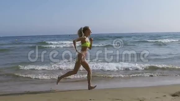 一个漂亮的女孩穿着比基尼在海滩上奔跑视频的预览图