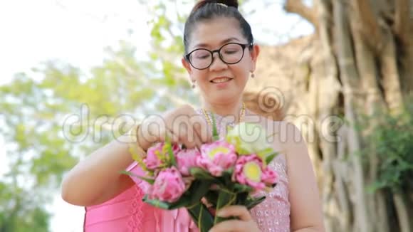 泰国女人牙齿般的笑脸手里拿着粉红色的莲花视频的预览图