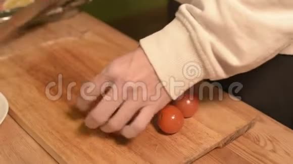一个女孩的手特写在家厨房的一块木制砧板上小樱桃西红柿家常菜视频的预览图