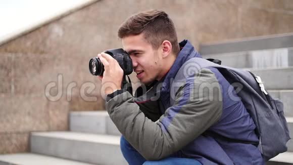 年轻的帅哥用自己的相机和微笑拍照视频的预览图