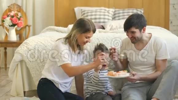 小可爱的男孩和爸爸妈妈在卧室里吃蛋糕视频的预览图