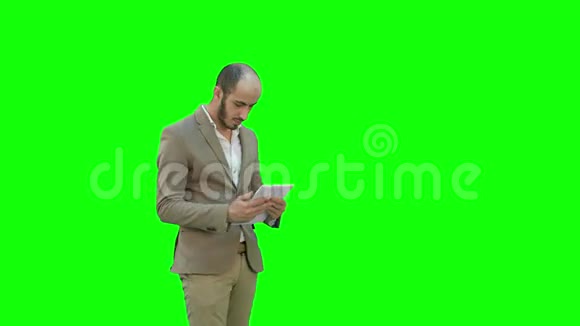 年轻的商人在绿色屏幕上使用平板电脑Chroma键视频的预览图