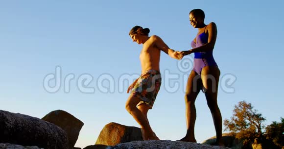 两人手牵手走在岩石上视频的预览图