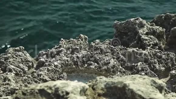 海湾沿岸的老岩石被风和石头的波浪所模糊视频的预览图