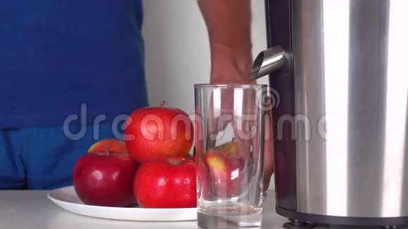 穿蓝色衣服的人用闪亮的榨汁机做红色苹果汁4K近距离射击视频的预览图