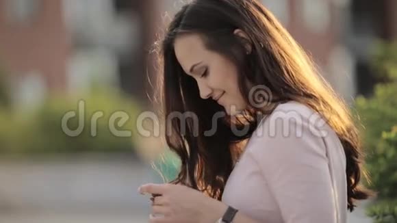 年轻美丽的女人在街上打电话留言视频的预览图