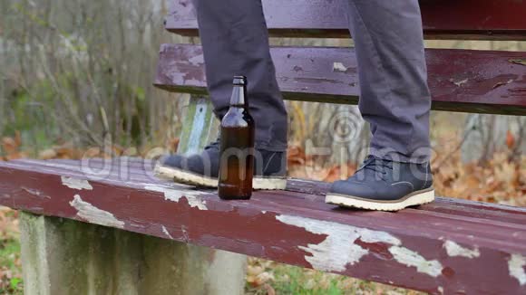 公园长椅上一个男人腿上的啤酒瓶视频的预览图