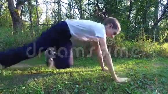 瘦小的男孩被从森林里的地上拧下来男孩被训练成更强壮自然运动视频的预览图