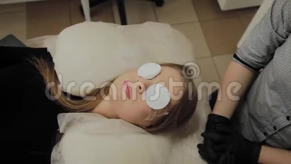 一个非常漂亮的女孩在美容院做一个层叠睫毛等待睫毛上的胶水干燥视频的预览图