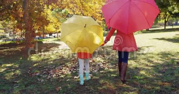母亲和女儿带着雨伞走在户外视频的预览图