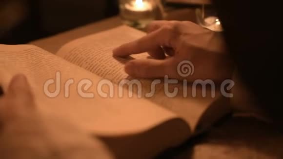 大特写女魔术师在一个黑暗的房间里烛光在寻找一本书中的咒语低键带电摄像机神秘视频的预览图