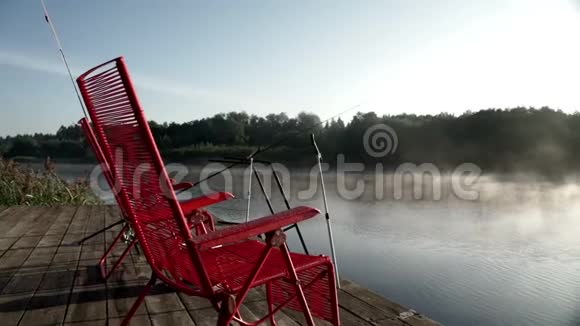 美丽的晨景红色的椅子站在背景雾的渔墩上视频的预览图