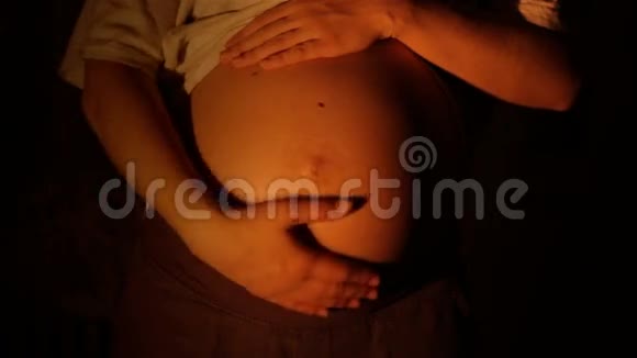 孕妇在黑暗背景下按摩腹部视频的预览图