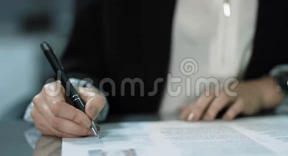 4K一位年轻的经理正在她的办公桌前签合同这位女士穿着一件白色上衣上面有一件黑色夹克视频的预览图