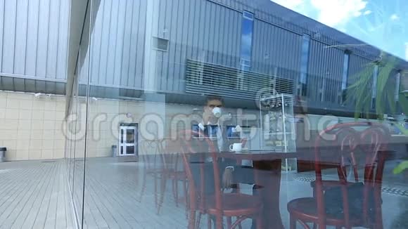 商人喝咖啡坐在明亮的咖啡馆里从大镜子窗口观看视频的预览图