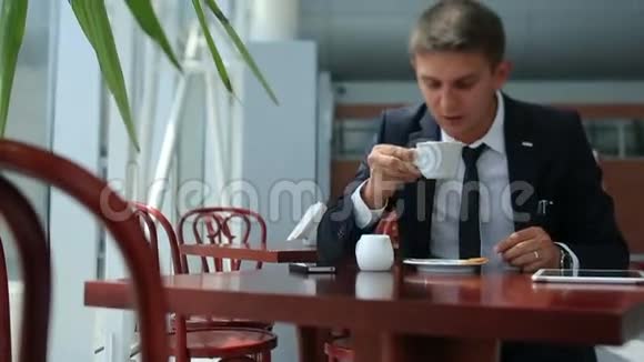 商务人士一边喝咖啡一边打电话坐在明亮的咖啡馆里视频的预览图