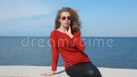 时尚流行太阳镜上的女性特写肖像手挽卷发在沙滩上海风吹拂视频的预览图