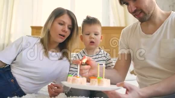 一家人笑着一起庆祝儿子的生日然后在蛋糕上点蜡烛视频的预览图