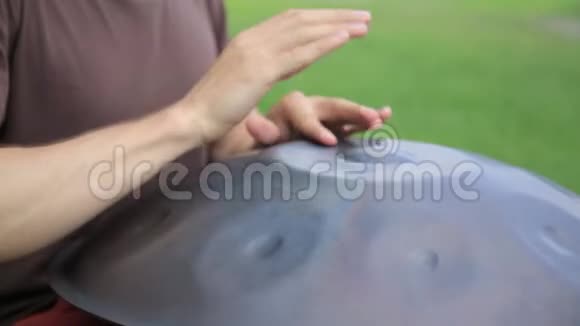 鼓手在行动坐在草地上玩手盘或挂鼓的家伙视频的预览图