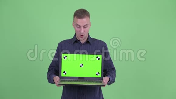 快乐英俊的商人展示笔记本电脑看上去很惊讶视频的预览图