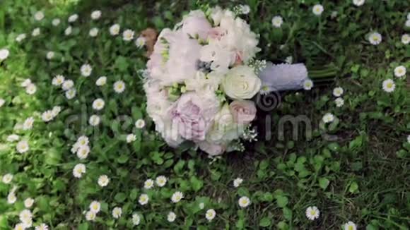 婚礼上的一束粉红色玫瑰和牡丹躺在绿草上周围是洋甘菊周围没有人外部视频的预览图
