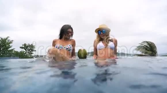 在游泳池里漂浮的女孩在游泳池里泼水和一个女孩在酒店的游泳池里休息视频的预览图