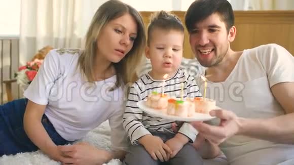 微笑的家人一起庆祝他们的儿子生日在蛋糕上吹蜡烛视频的预览图