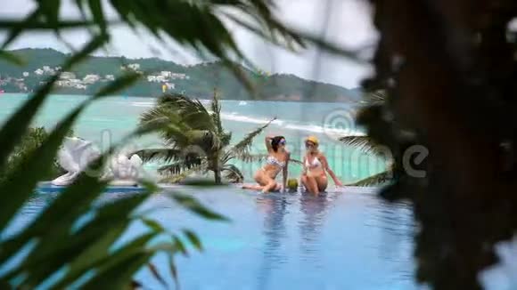 在游泳池里漂浮的女孩在游泳池里泼水和一个女孩在酒店的游泳池里休息视频的预览图