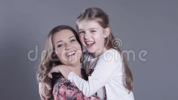 美丽而快乐的年轻母亲在工作室拥抱她可爱的女儿视频的预览图