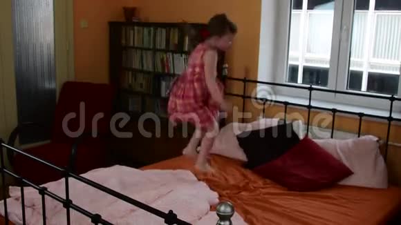 一个可爱的小女孩在床上跳父母的卧室和她的女儿正在床上跳跃视频的预览图