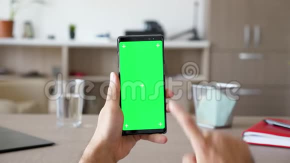 客厅里的人拿着一部带有绿色屏幕色度的智能手机视频的预览图