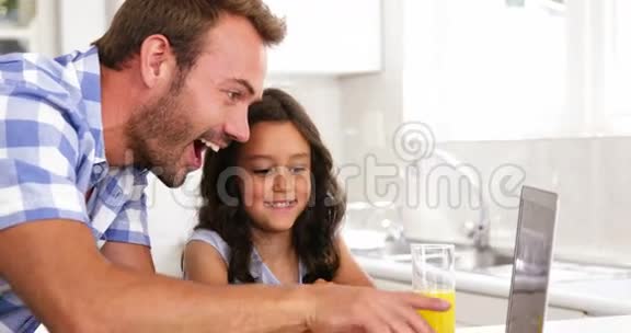 女儿和父亲在笔记本电脑前大笑视频的预览图