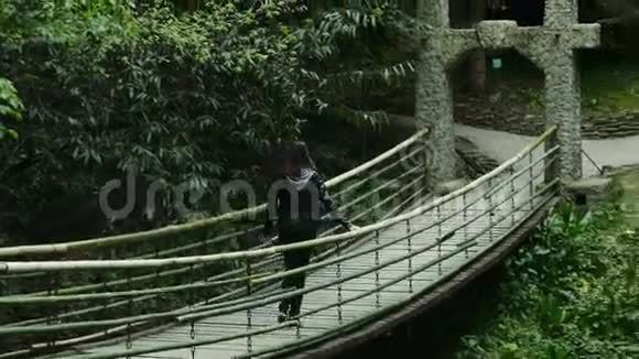 女孩在茂密的森林中上吊桥视频的预览图