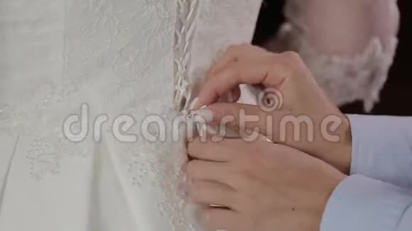 在年轻新娘的后面准备婚礼妈妈帮女儿穿婚纱视频的预览图